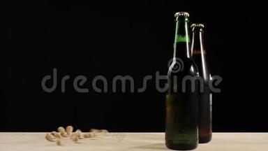 新鲜啤酒。 在木桌上放着美味的手工啤酒，放在绿色和棕色瓶子附近